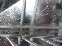 Bliski widok kratki kosza zmywarki z niewielkimi śladami rdzy.