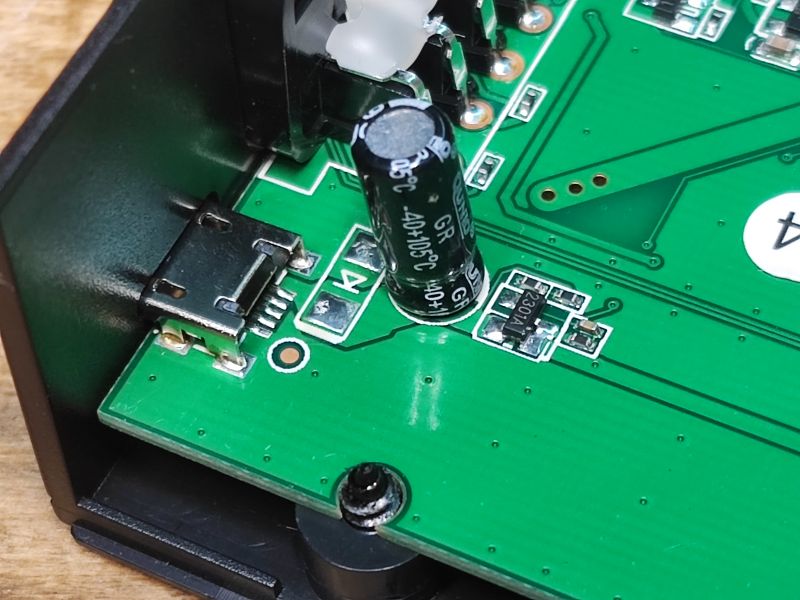 Zbliżenie na płytkę drukowaną dekodera Opticum Blue R265 Lite z wtykiem micro USB, kondensatorem i elementem oznaczonym jako 2301A.