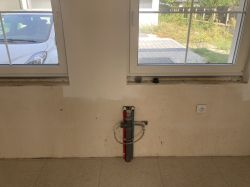 Rury instalacyjne przy ścianie pod oknem.