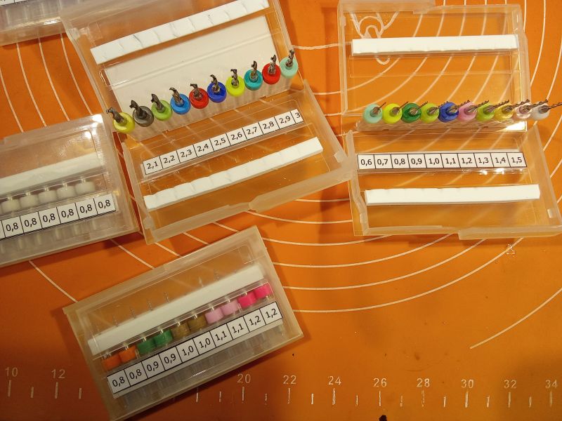 Zestawy wierteł o różnych średnicach w plastikowych opakowaniach.