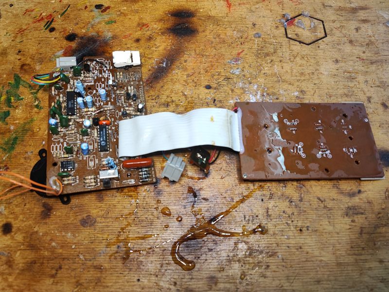 Wnętrze telefonu stacjonarnego z lat 90., płytki drukowane na drewnianym blacie.