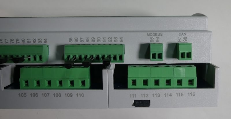 Zielone złącza zaciskowe na szarej obudowie urządzenia, z numeracją i opisami „MODBUS” oraz „CAN”