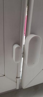 White sensors mounted on a window, one on the sash, the other on the frame.