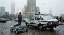 Polish officer and Milicja car next to large Arduino board on wheels in foggy Warsaw