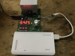 Biały powerbank Romoss podłączony do elektronicznego testera, wyświetlacz pokazuje wartość 6.423.