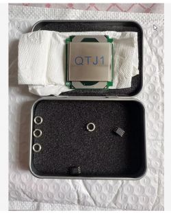 Procesor oznaczony jako QTJ1 w metalowym pudełku z podkładkami i układami scalonymi.