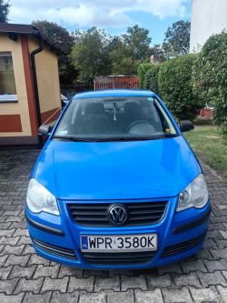 A blue Volkswagen car parked in a driveway in front of a house.