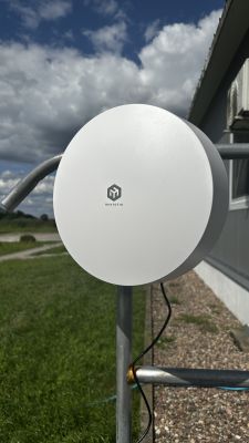 Zewnętrzna antena MikroTik zamontowana na metalowym słupku przy budynku