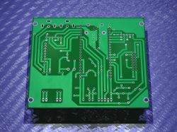 Bottom view of a green PCB with mounting holes and through-hole traces