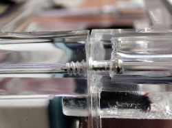 Close-up of a screw and nut fastener in a transparent acrylic enclosure