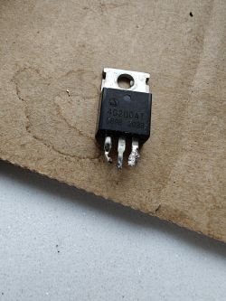 Tranzystor MOSFET 4C200AT z trzema wyprowadzeniami, leżący na kawałku tektury.