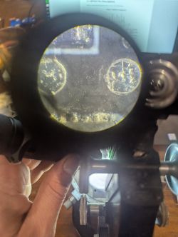 View through a round lens: close-up of a metal part with two screws