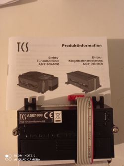 Urządzenie TCS ASI21000 z instrukcją na tle.