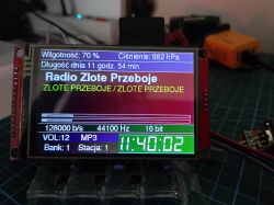LCD module on a workbench showing “Radio Złote Przeboje” interface with weather data, audio info, and a clock