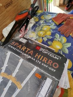 Pudełko anteny zewnętrznej OPTICUM SPARTA HIRRO na stole obok piły i rękawic.