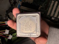 Procesor AMD K6-2 trzymany w ręce z nałożoną pastą termoprzewodzącą