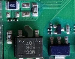 Zbliżenie płytki PCB z elementami SMD i oznaczeniem rezystora „1R00”