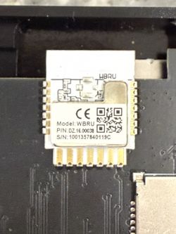 Electronic module with certification marks and serial numbers on a dark circuit board.