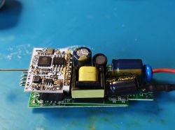 Płytka elektroniki z układem ESP8266EX i elementami zasilacza na niebieskiej macie