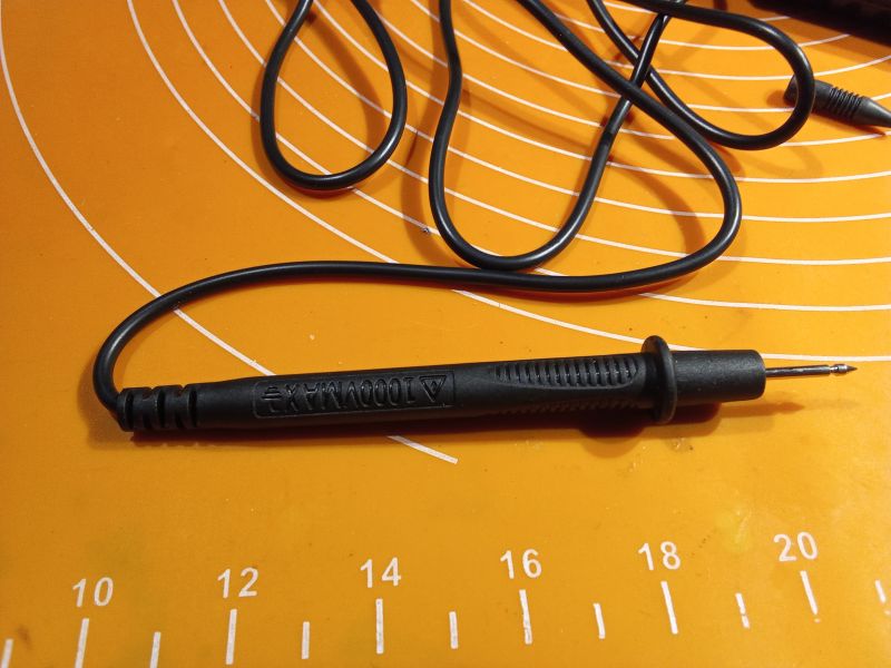 Czarna sonda pomiarowa z przewodem na pomarańczowym tle.