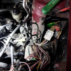 Silnik samochodu z widoczną plątaniną przewodów i kabli, w tym kabel oznaczony czerwoną taśmą.