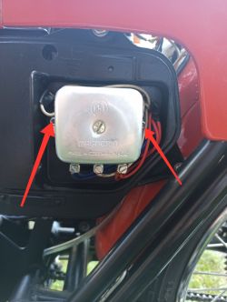 Zbliżenie na regulator napięcia w motocyklu, z zaznaczonymi dwoma białymi przewodami.