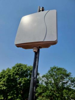 Zewnętrzna antena internetowa montowana na maszcie na tle nieba.