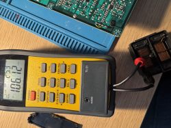 Miernik cyfrowy mierzący rezystancję w układzie elektronicznym na stole roboczym.