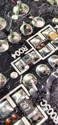 Zbliżenie na płytkę drukowaną z widocznymi elementami elektronicznymi, w tym rezystory.