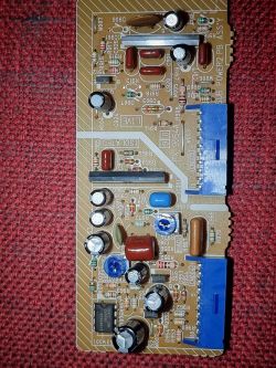 Zdjęcie płytki drukowanej z różnymi komponentami elektronicznymi na czerwonym tle.