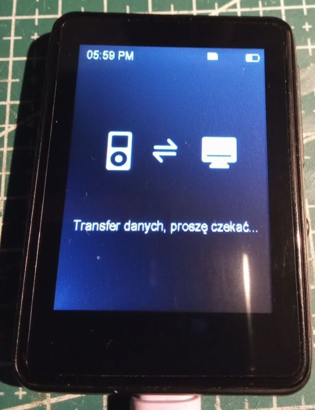 Ekran małego urządzenia z ikonami transferu i tekstem „Transfer danych, proszę czekać...”