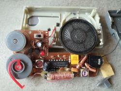 Interior of an old portable radio showing the circuit board, speaker, and electronic components.