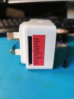 An electronic adapter with a plug and a pin header labeled on a red sticker