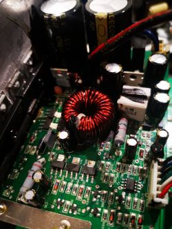 Zbliżenie na płytkę elektroniczną z widocznymi kondensatorami i cewką indukcyjną.