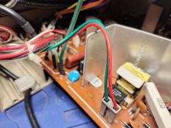 Zbliżenie na wnętrze monitora z dwoma przewodami w plastikowej wtyczce na płytce PCB