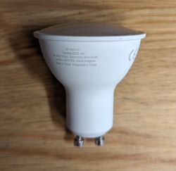 LED Bulb Lepro GU10 with Close-up on Markings LED bulb Lepro GU10 lying on a wooden surface, showing the lower part with printed information.