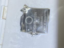 Crumpled silver lithium battery labeled “QWNB 2028N” on a white surface