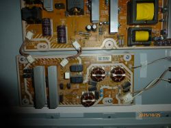 Zbliżenie na wnętrze telewizora z widocznymi płytami zasilającymi i elementami elektronicznymi.