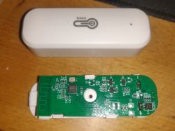 Disassembled electronic device with a circuit board next to its casing.