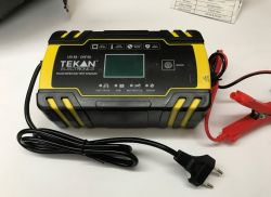 TEKAN Electronics battery charger with LCD display, power cord, and battery clamps.