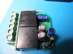 Electronic module with capacitors and screw terminals on a blue background.