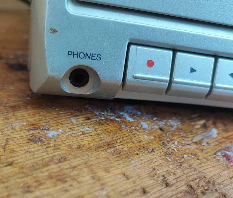 Zbliżenie na panel starej wieży audio z widocznym gniazdem Phones i przyciskami.