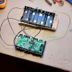 Replacing Cells in Dreame V9 Battery Setup of Dreame V9 battery and circuit board on cardboard.