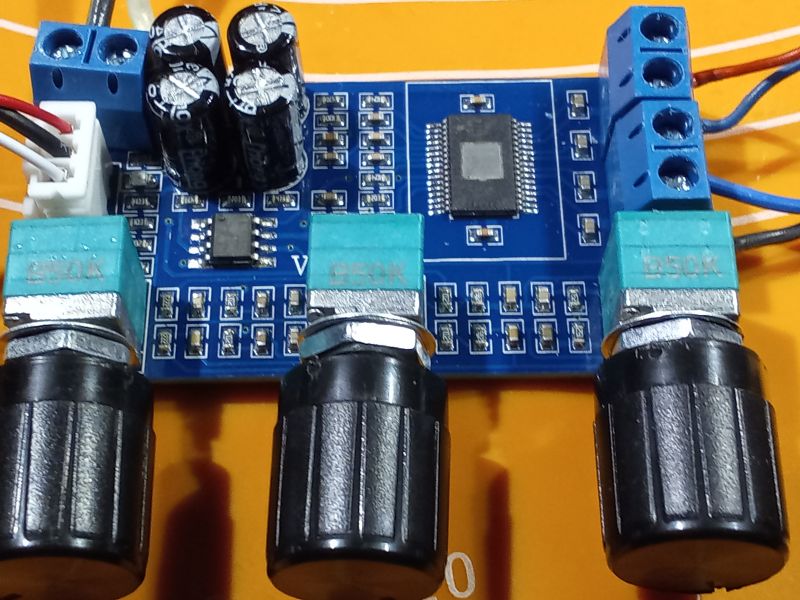 Zbliżenie na płytkę obwodu drukowanego z elementami elektronicznymi, takimi jak potencjometry, kondensatory i złącza.
