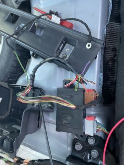 Podłoga wnętrza samochodu z widocznymi przewodami elektrycznymi i modułem haka holowniczego.