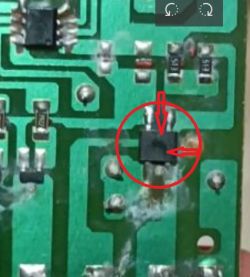 Zbliżenie uszkodzonego elementu elektronicznego na płytce PCB, zaznaczonego czerwonym okręgiem.