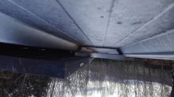 Widok spod paneli fotowoltaicznych na dachu, z bliska widać profil montażowy i krawędź panelu.