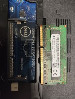 Gniazdo pamięci RAM w laptopie Dell z modułem RAM DDR3 obok.