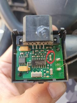 Zbliżenie na płytkę układu elektrycznego z zaznaczonym na czerwono kondensatorem.