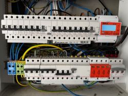 Widok wnętrza rozdzielnicy elektrycznej z bezpiecznikami i okablowaniem.